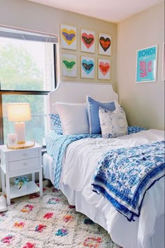 a white bed sitting in a bedroom next to a window with pictures on the wall