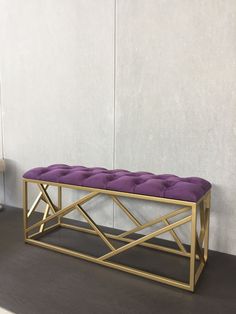 a purple bench sitting on top of a wooden floor next to a white and gray wall