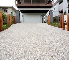 an empty driveway in front of a two story house with wooden balconies on the second floor