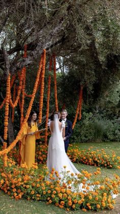 the bride and groom are standing in front of an orange flower garden with flowers all around them