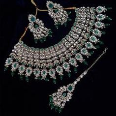 an elaborate necklace and earring set with green stones on the bottom, along with matching earrings