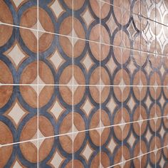 a tiled wall with blue and brown circles on it's sides, in a bathroom