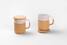 two coffee mugs sitting next to each other on a white surface with no one around them