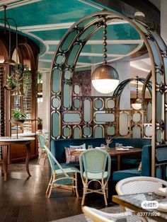 the inside of a restaurant with blue chairs and tables in front of an arched glass wall