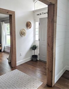 an entryway with two hats on the wall and a rug in front of it