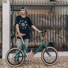 a man standing next to his bike in front of a gate