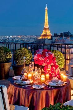 the table is set with candles and flowers in front of the eiffel tower