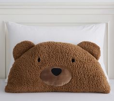 a brown teddy bear pillow sitting on top of a bed