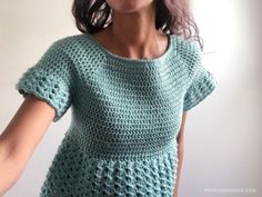 a woman wearing a green crochet top and holding her hands out to the side