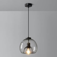 a clear glass light fixture hanging from a ceiling in a room with gray walls and flooring