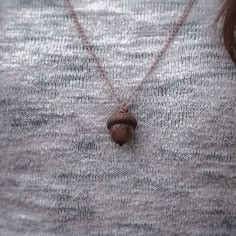 a woman wearing a necklace with an acorn on it