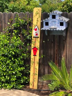 a bird house is painted on the side of a wooden pole in front of a fence