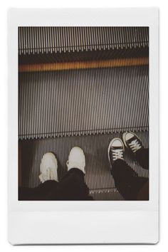 two people standing on an escalator with their feet propped up against the wall