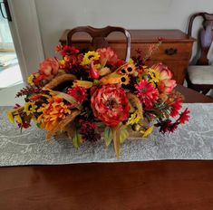 a wooden table topped with a vase filled with lots of colorful flowers on top of it