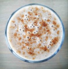 a glass filled with creamy chai latte on top of a wooden table