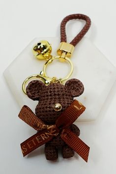 a keychain with a teddy bear on it and a bell attached to it