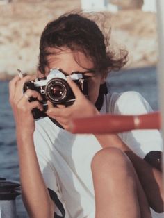 a person sitting on the ground with a camera in front of their face, taking pictures