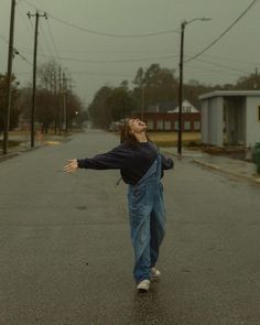 a woman is walking down the street with her arms spread out and she has her eyes closed