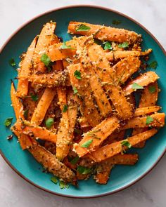 a blue plate topped with cooked carrots covered in seasoning