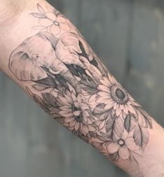 an elephant and flowers tattoo on the arm