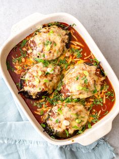 baked stuffed eggplant in a white casserole dish on a blue towel