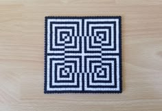 a piece of black and white quilted material on a wooden surface with squares in the center