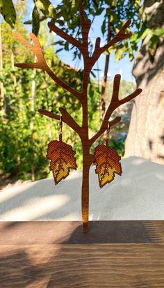 a wooden tree with earrings hanging from it's branches in front of some trees