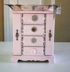 a pink dresser with silver handles and knobs on it's drawers is sitting on a table