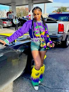 a woman standing next to a car in a parking lot wearing colorful clothing and furry boots