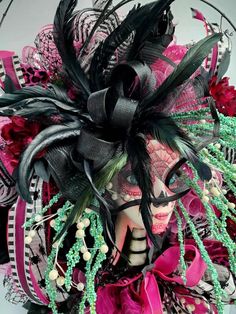 a close up of a woman's face wearing a mask with feathers and beads