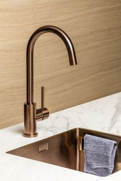 a kitchen sink with a towel hanging from the faucet and marble counter top