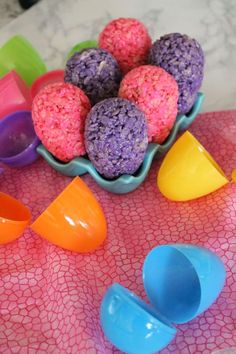 there are many different colored plastic objects in the bowl on the counter top, including balls and spoons