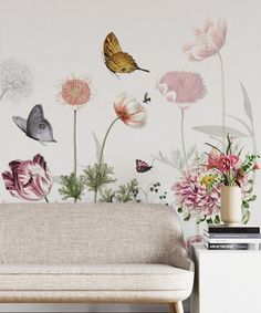 a couch in front of a wall with flowers and butterflies painted on the wall behind it