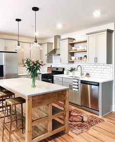 a large kitchen with an island in the middle and stainless steel appliances on both sides