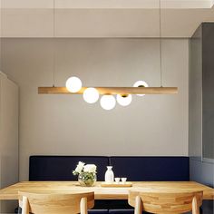 a dining room table with four chairs around it and lights hanging from the ceiling above