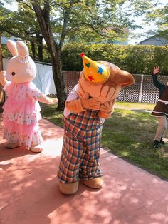 two people dressed up as bunnies and bunny dolls on a sidewalk in front of some trees