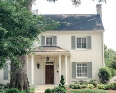 a large white house with trees and bushes around it