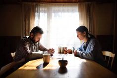 two people sitting at a table in front of a window