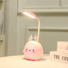 a pink lamp sitting on top of a table next to a stack of books and a box