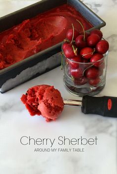 cherries in a bowl next to an ice cream scooper and cherry sorbet