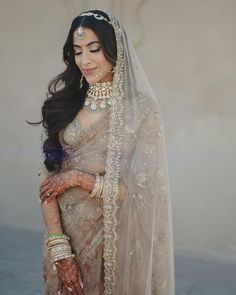 a woman in a bridal gown and veil with jewelry on her head is posing for the camera