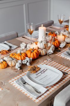 the table is set with pumpkins, candles and napkins on it for thanksgiving dinner