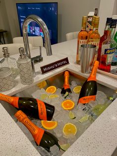 there are bottles and oranges in the ice cube on the counter top next to the sink