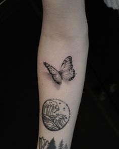 a butterfly flying over the top of a tree and wave tattoo on someone's arm