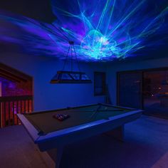 a pool table in a room with blue lights on the ceiling and a light fixture hanging from the ceiling