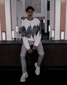 a man sitting on top of a counter next to a white tiled wall with columns