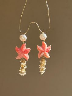 Joyful summer earrings, ideal for a beach vacation! Two starfish are made of carved conch shell, adorned with cascade of tiny fresh water pearls. The pearl studs are 18k gold filled.  MATERIAL Conch shell, freshwater pearls, gold filled   SPECIFICATIONS Length 6 cm Handmade in Spain Earrings come in a gift box Worldwide shipment with registered, trackable post Care for gold filled jewelry: avoid contact with humidity, swimming pool water and chemicals. Clean with soft dry polishing cloth.  Care White Starfish Ocean-inspired Earrings, Handmade Starfish Earrings For Beach, Ocean-inspired Drop Earrings With Starfish Charm, Ocean-inspired Starfish Charm Dangle Earrings, Summer Shell Starfish Jewelry, Summer Starfish Shell Jewelry, Summer Beach Earrings With Starfish Charm, Summer Starfish Charm Dangle Earrings, White Starfish Earrings For Beach