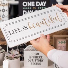 a person holding up a sign that says life is beautiful