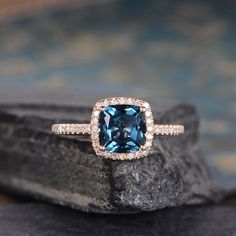 a blue cushion cut diamond ring on top of a rock