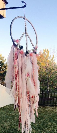 a wind chime hanging from the side of a building with flowers and feathers on it